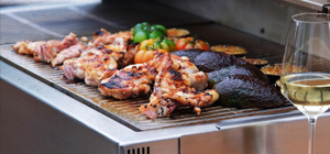 Durchgebratenes Fleisch und Gemüse liegen auf eine Grillfläche.