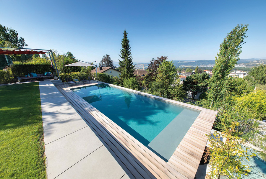 Swimmingpool umrahmt von einer Holzterrasse mit schönem Ausblick